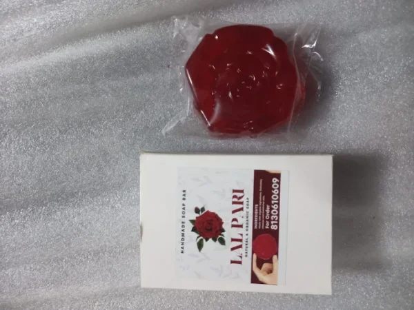 Red rose-shaped soap placed next to its packaging listing benefits for skin care.